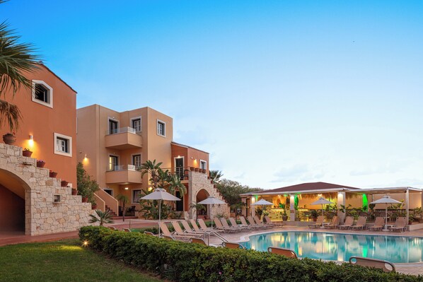 A hotel with a swimming pool, lounge chairs, and a restaurant area. - Dia Apartments (Hersonissos)