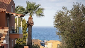 A coastal building with a balcony overlooking the sea, a palm tree, and a clear view of the ocean. - Dia Apartments (Hersonissos)