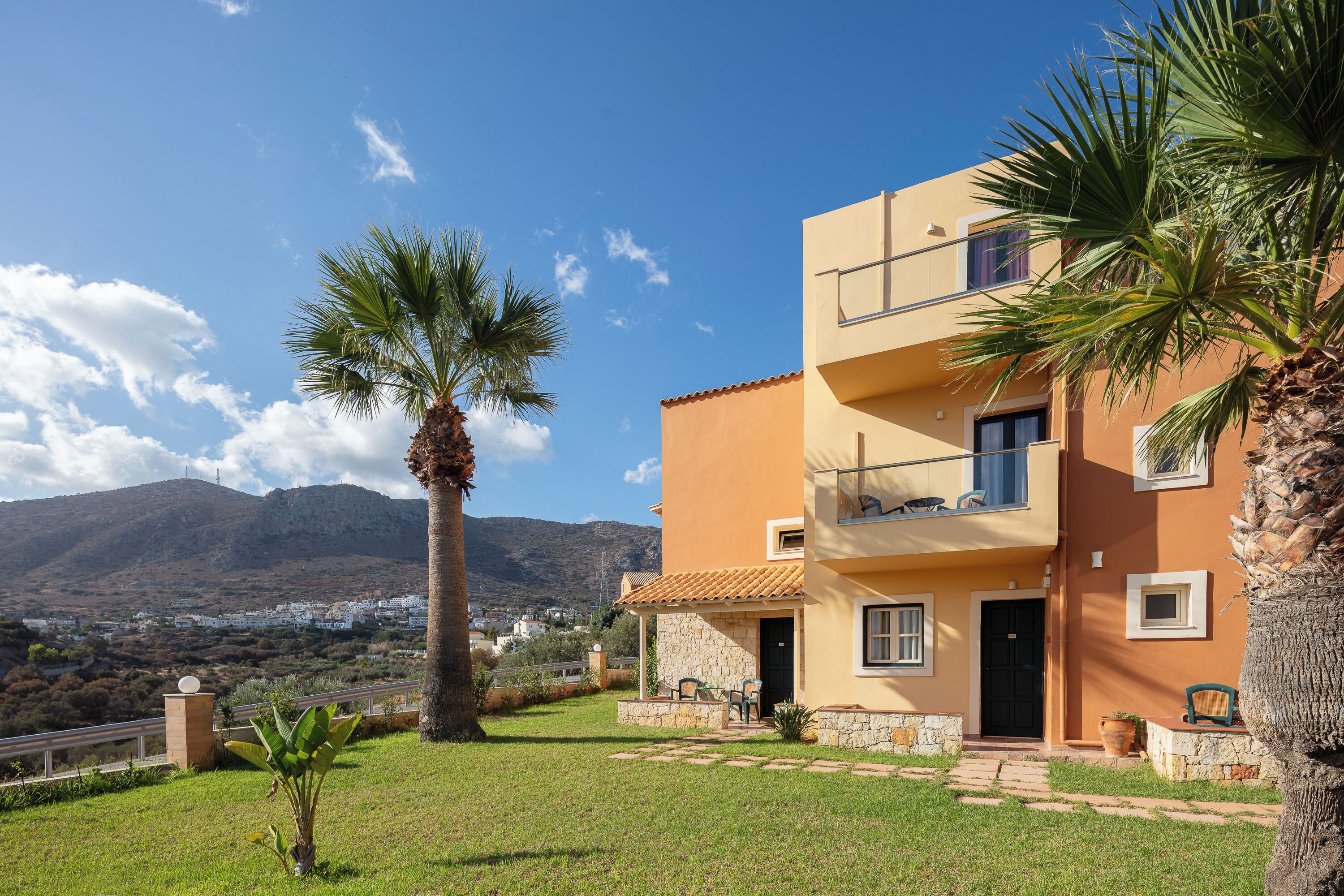 A two-story building with a balcony, a stone base, and a view of a mountainous landscape.