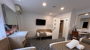 Una habitación de hotel con cama, escritorio, espejo y baño.