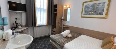 A hotel room with a bed, a large window with curtains, a bathtub, a sink, a mirror, and a television.