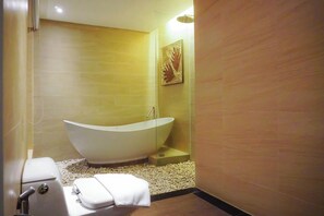 Een moderne badkamer met een vrijstaand bad, een toilet en een douchecabine.