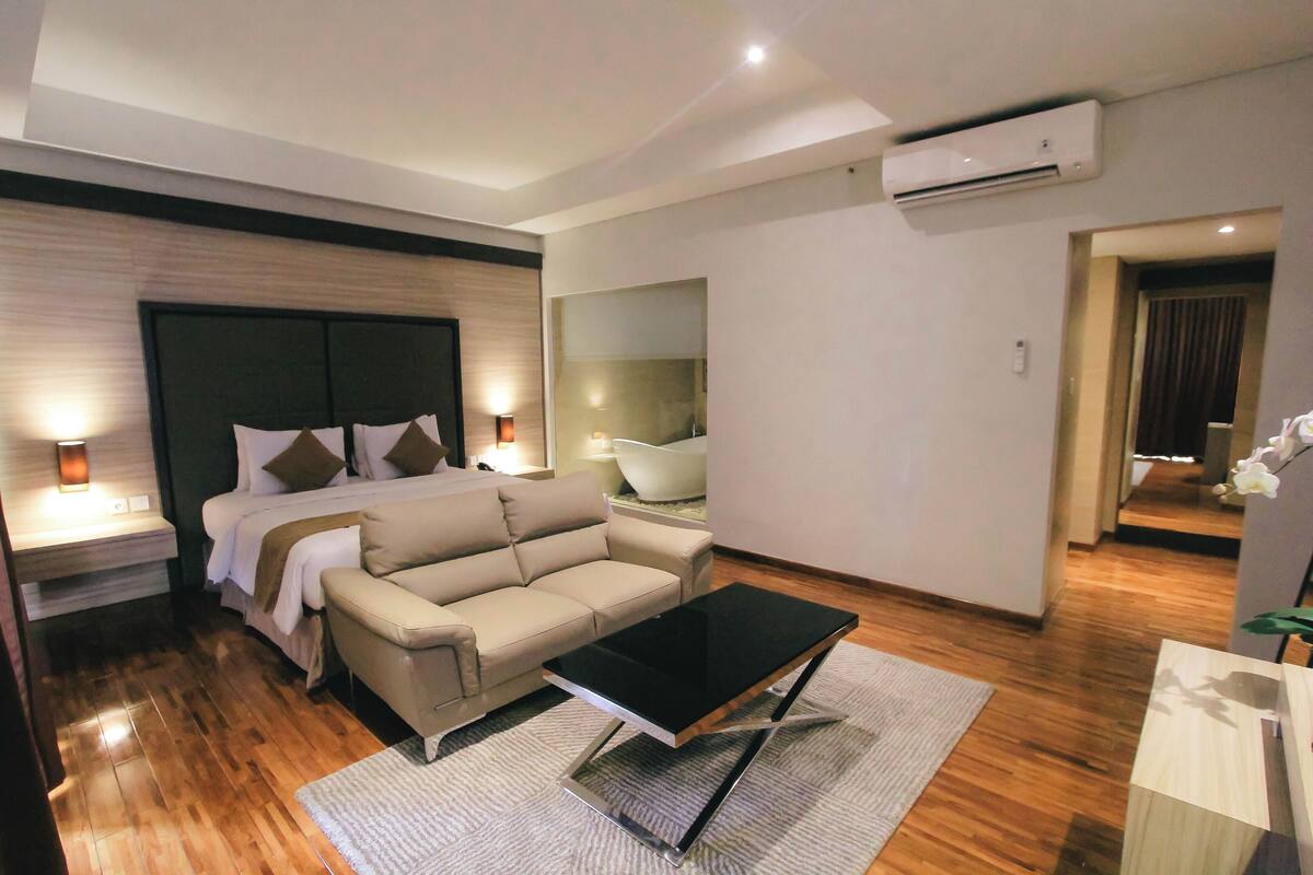 Una habitación de hotel moderna con cama, sofá y una mesita de café.