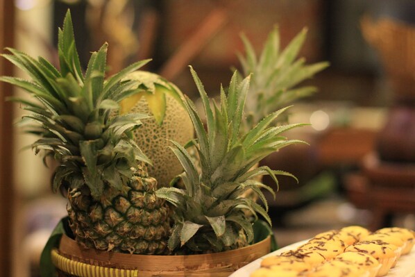Un saladier en bois contenant des ananas et un melon.