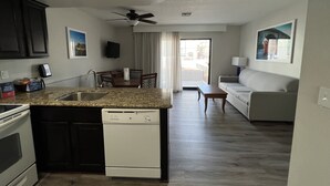 A modern kitchen with a built-in dishwasher, a dining area with a table and chairs, a living room with a sofa, and a ceiling fan. - GetAways at Havasu Dunes Resort (Lake Havasu City)