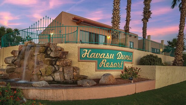 A sign for Havasu Dunes Resort with a stone waterfall feature in front. - GetAways at Havasu Dunes Resort (Lake Havasu City)