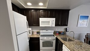 A modern kitchen with dark wood cabinets, white appliances, and a granite countertop. - GetAways at Havasu Dunes Resort (Lake Havasu City)