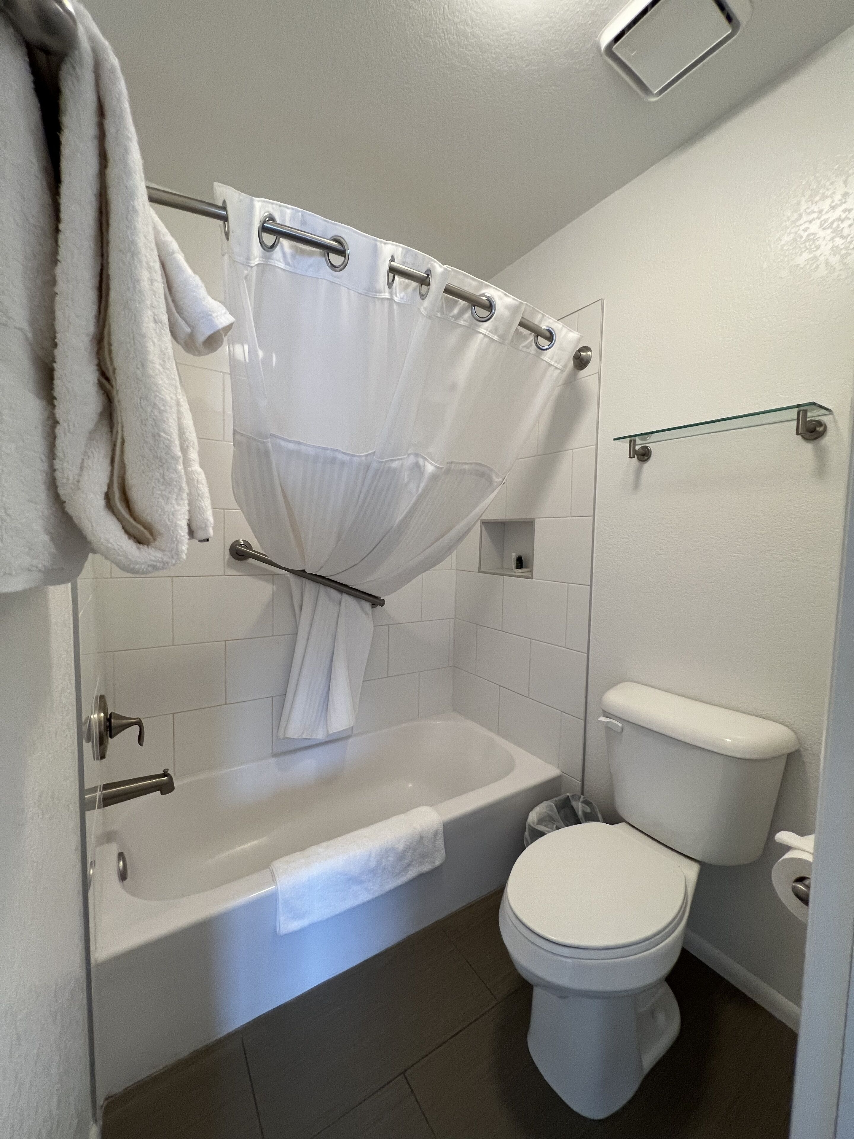 A bathroom with a bathtub, toilet, and shower curtain.
