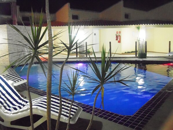 Una piscina con sillas de descanso y palmeras.