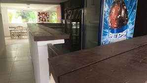 A kitchen area with a wooden countertop, a refrigerator, and a dining table with chairs. - Recanto Tropical Hotel (Guarujá)