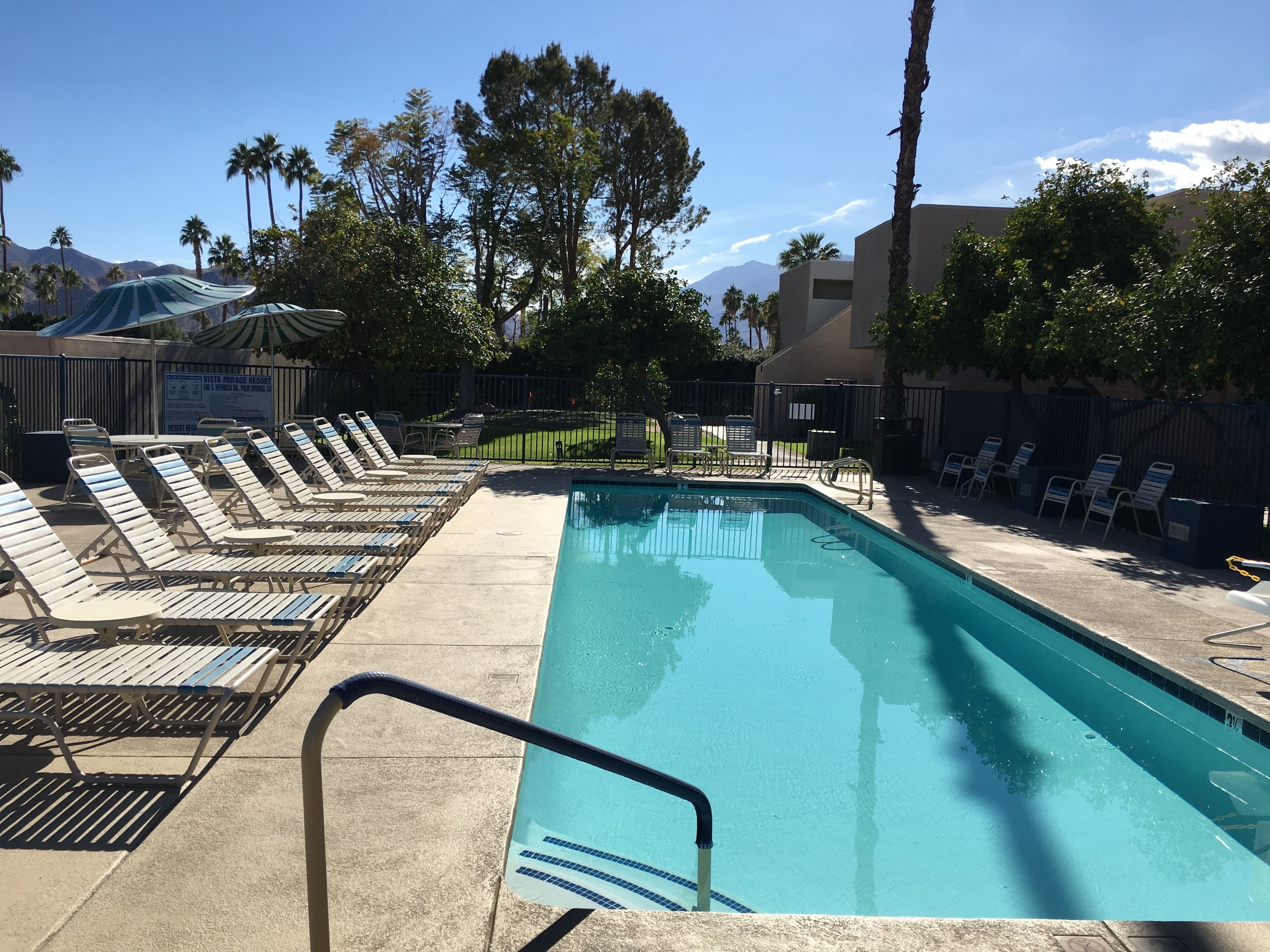 Un área de piscina con sillas de descanso y un cartel para el Resort Vista Mirage.