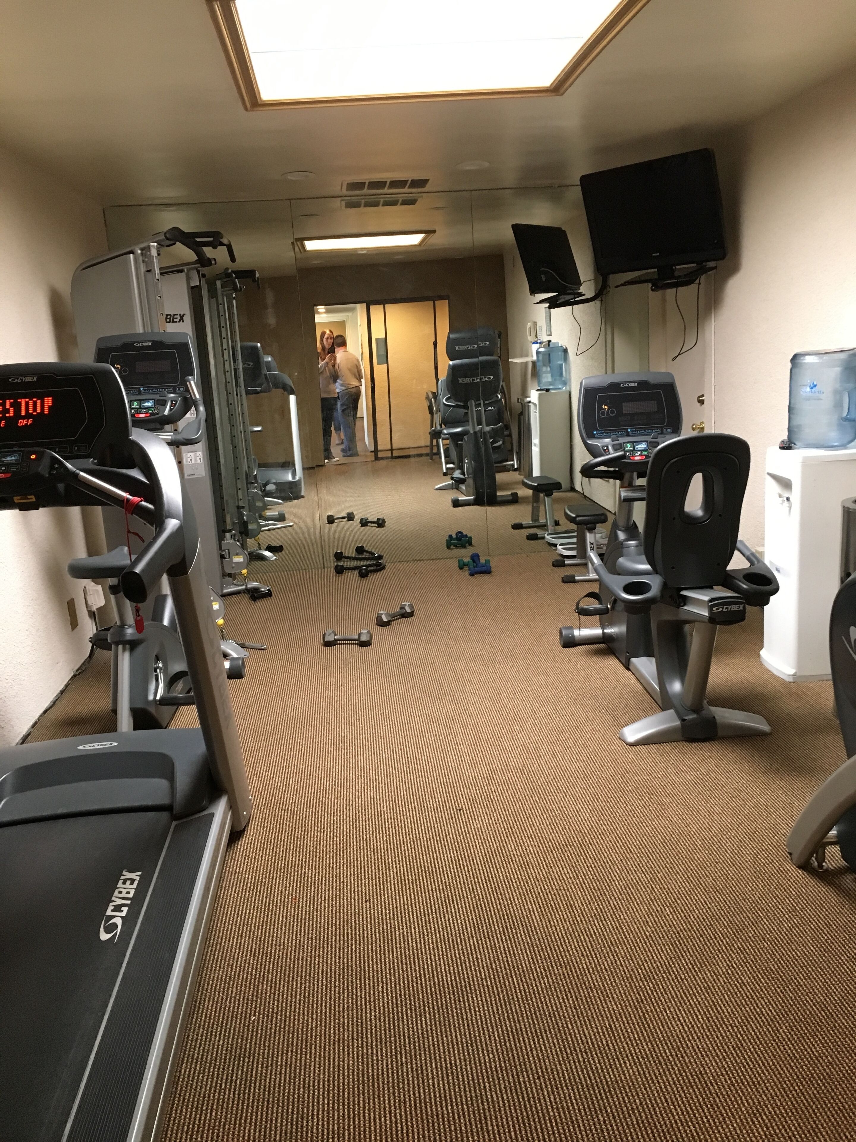 Un gimnasio con cintas de correr, máquinas de pesas y mancuernas.