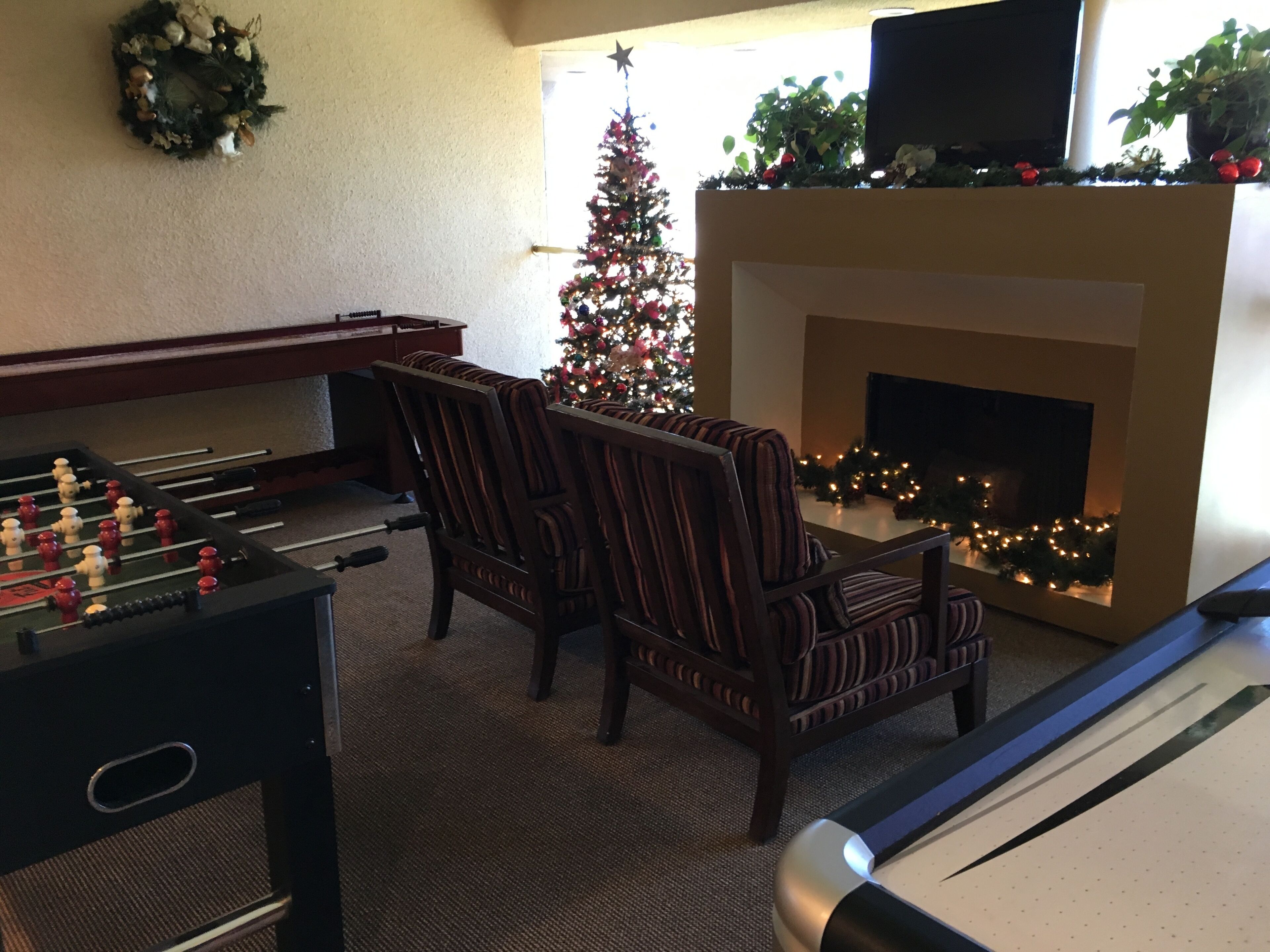 A living room with a foosball table, a fireplace, and a Christmas tree.