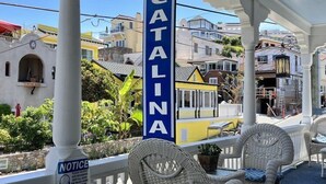 A hotel named 'Hotel Catalina' with a covered outdoor seating area featuring wicker chairs and a blue carpet. - Studio 9 Hotel Catalina (Avalon)