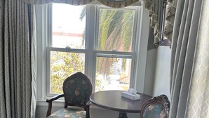 A room with two ornate chairs, a round table, and a large window with curtains. - Studio 9 Hotel Catalina (Avalon)