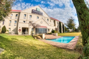 Um hotel com piscina, telhado vermelho e uma placa que diz 'Road Lodge by City Lodge Hotels'.