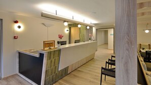 A reception area with a counter, a mirror, and a seating area with chairs. - Road Lodge N1 City (Cape Town)