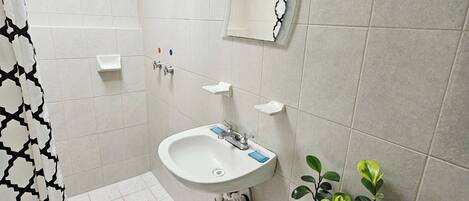 A bathroom with a shower, sink, toilet, and a mirror.