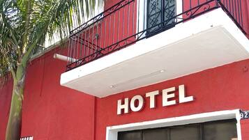 A red building with a balcony and a sign that reads "HOTEL".