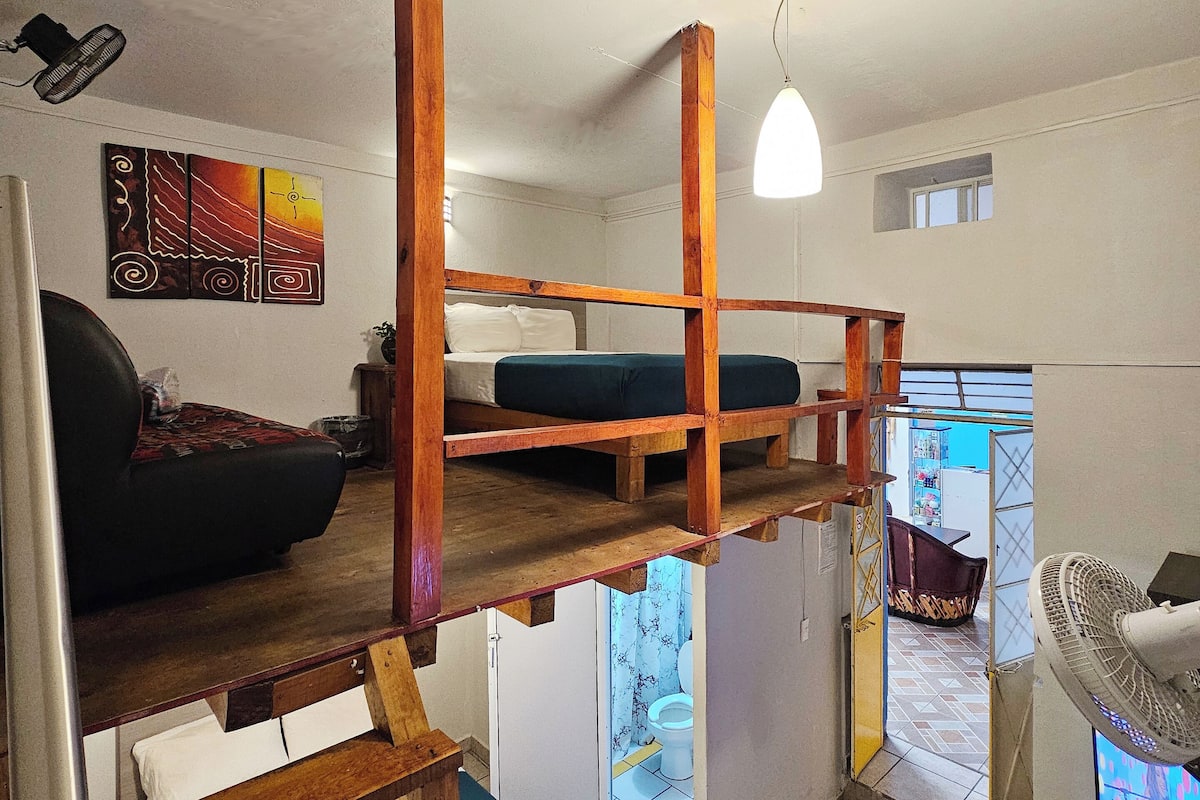 Una habitación funcional con literas, una mesa de comedor, una pequeña cocina y vistas al exterior.