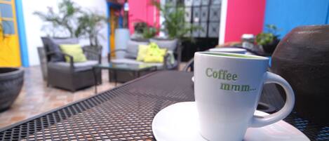 A white coffee mug with "Coffee mmm..." on a saucer on a metal table.