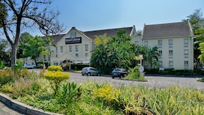 Un hotel con un cartel que dice "ROAD LODGE BY CITY LODGE HOTELS", rodeado de exuberante vegetación y palmeras.