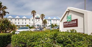 A hotel with a sign reading "Road Lodge by City Lodge Hotels," surrounded by greenery and parked cars. - Road Lodge Gqeberha (Gqeberha (Port Elizabeth))