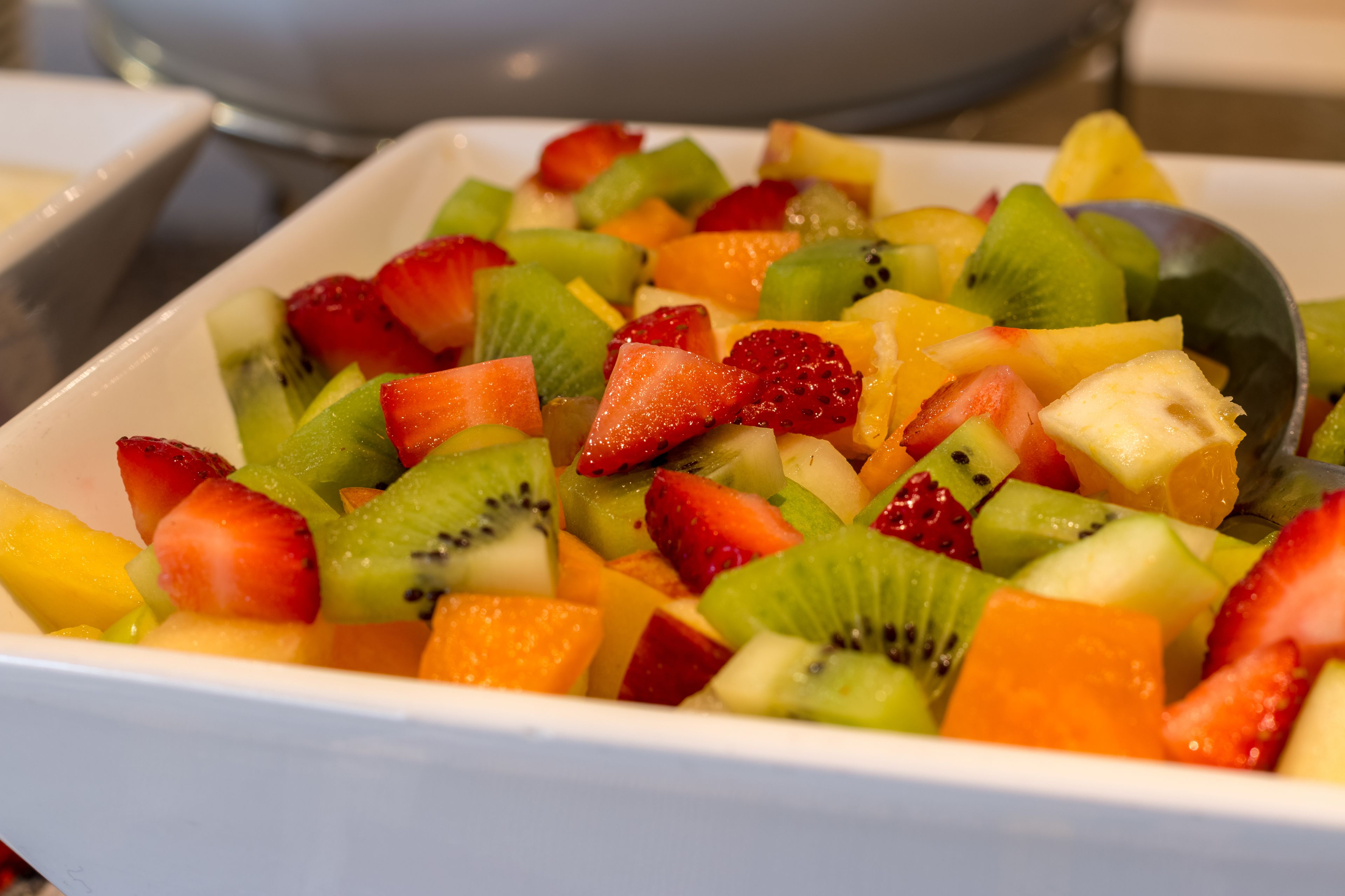 Un tazón de ensalada de frutas con fresas, kiwi, piña y melón.