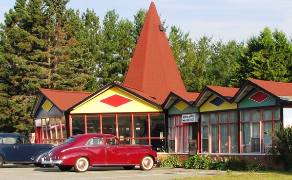 A motel with a red roof and yellow and green exterior.