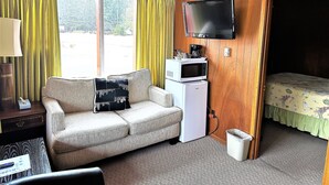 Et hotelværelse med sofa, fjernsyn, mikroovn og seng.