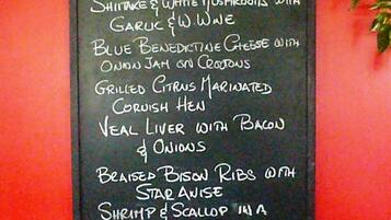 A chalkboard menu listing various dishes such as smoked whitefish chowder, white bean casserole, and grilled citrus marinated cornish hen.