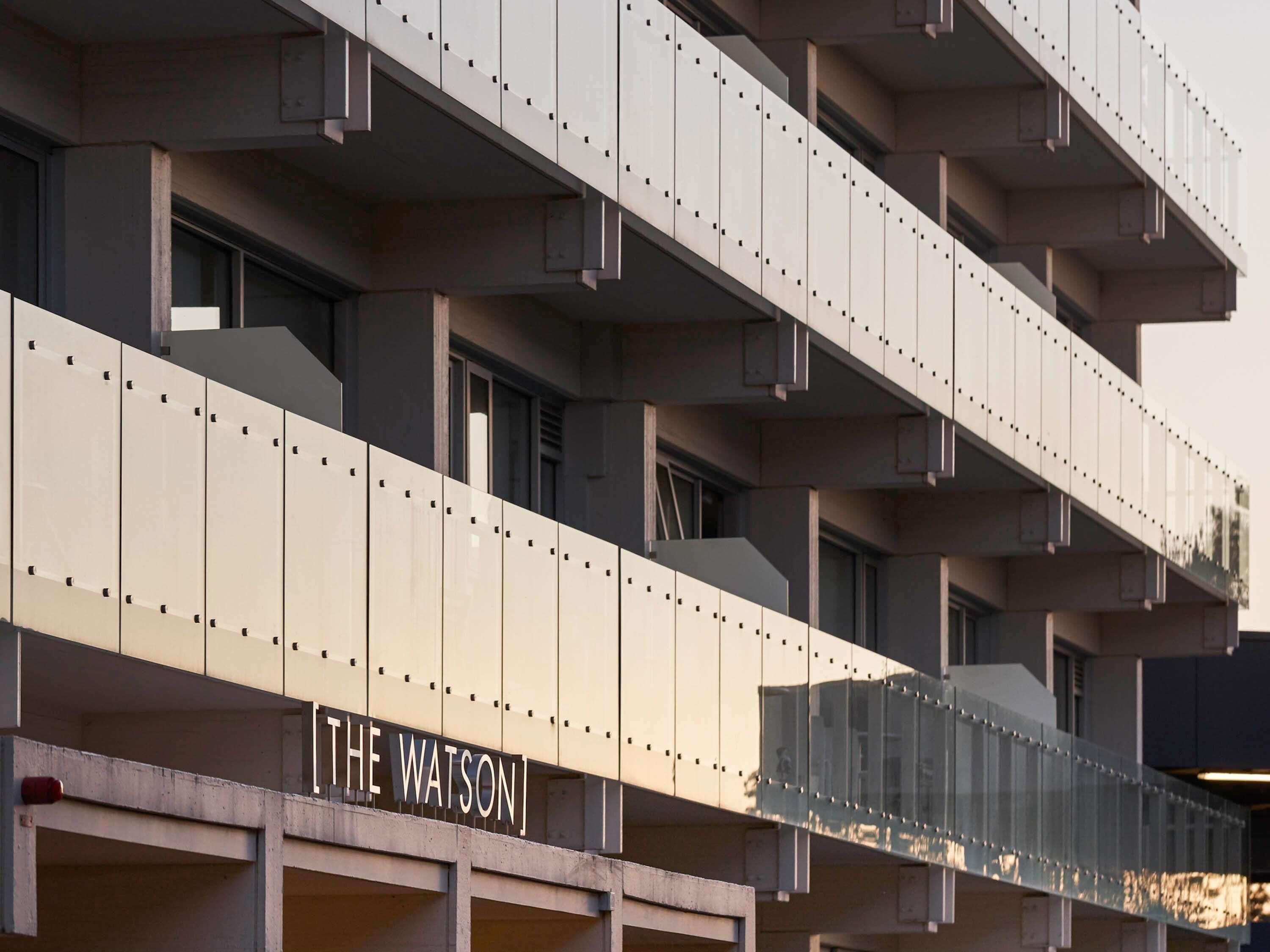 Un edificio de varios pisos con una serie de balcones y un letrero que dice 'THE WATSON'.