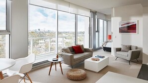A modern living room with a large window, a sofa, a coffee table, and a chair. - Art Series - The Watson (Walkerville)