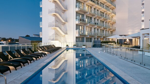 A modern hotel with a rooftop pool, multiple balconies, and a clear sky. - Art Series - The Watson (Walkerville)