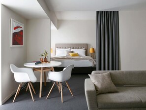Een moderne hotelkamer met een bed, een bank, een eettafel met stoelen en een schilderij aan de muur.