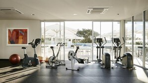 A gym with various exercise equipment, large windows, and a view of the outdoors. - Art Series - The Watson (Walkerville)