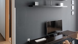 Un salon moderne avec un mur d’accent de couleur gris foncé, un téléviseur à écran plat, une table basse et un plancher en bois.