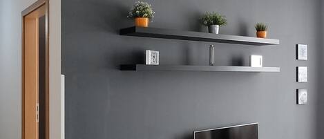 Una sala de estar moderna con una pared de acento gris oscuro, un televisor de pantalla plana, una mesita de centro y piso de madera.