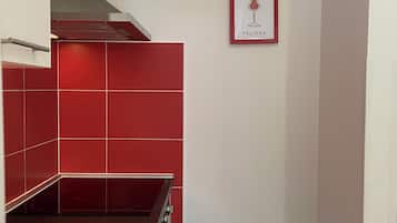 Una cocina con baldosas rojas, un lavamanos de acero inoxidable y un cuadro en la pared.