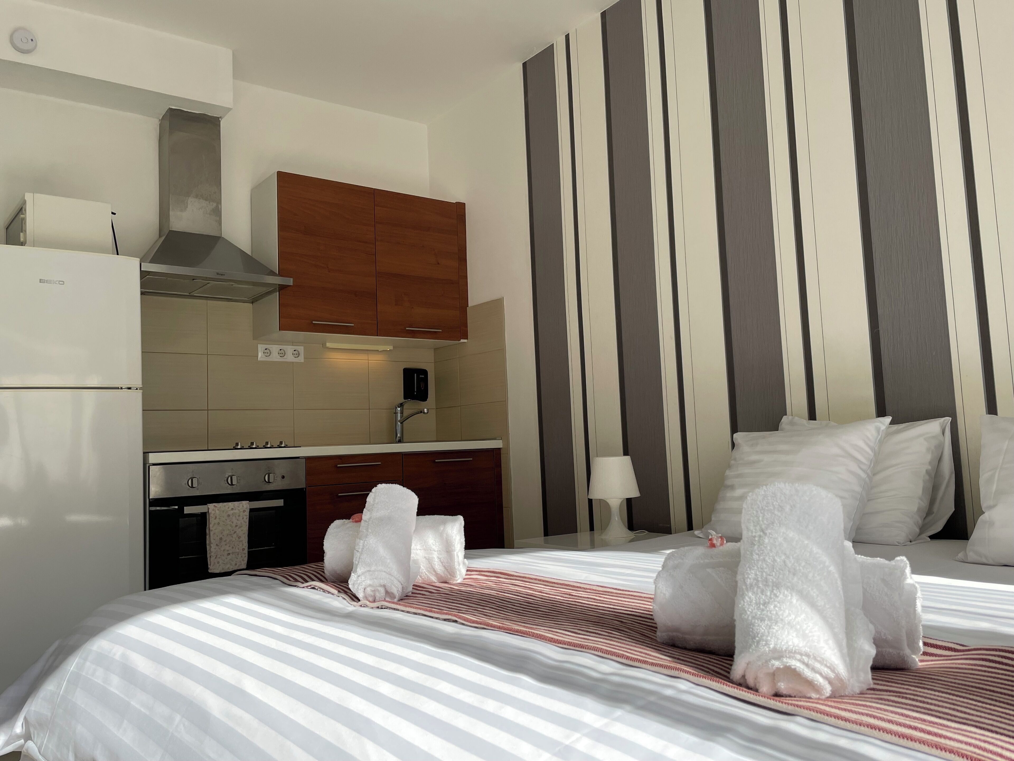 Une chambre d’hôtel avec un lit, un coin cuisine et un mur à rayures.