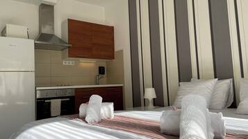Une chambre d’hôtel avec un lit, un coin cuisine et un mur à rayures.