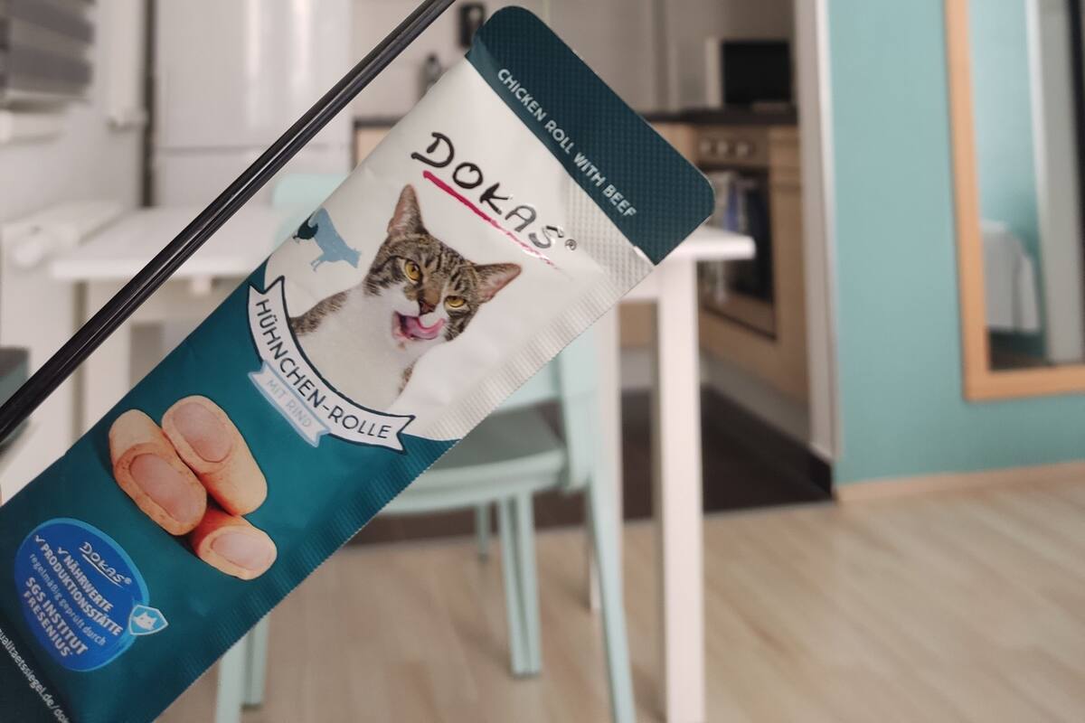A package of chicken rolls with beef, a feather toy, and a cat image on the packaging.