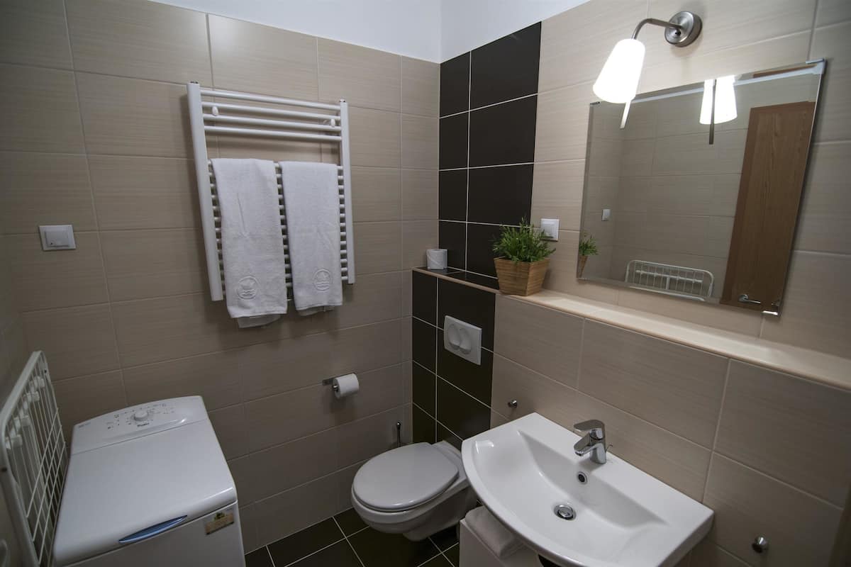 A modern bathroom with a toilet, sink, towel rack, and a mirror.