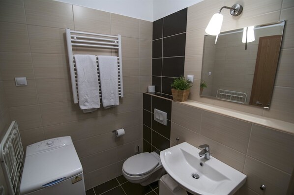A modern bathroom with a toilet, sink, towel rack, and a mirror.