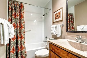 Un baño con ducha, inodoro, lavabo y espejo.
