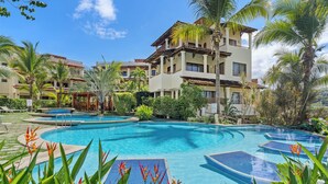 A resort with a large swimming pool surrounded by palm trees and tropical plants. - Tropical Gardens (Sardinal)