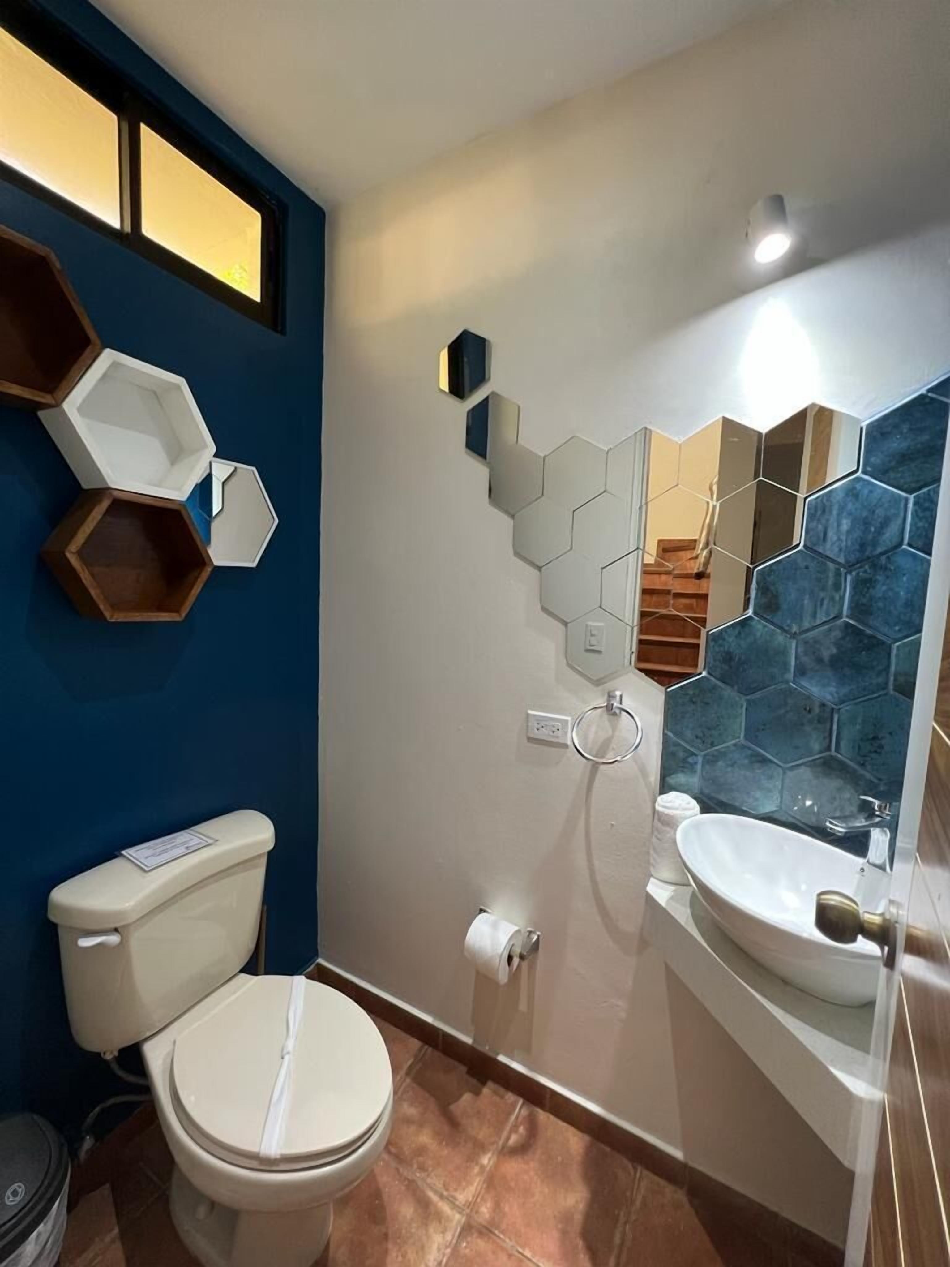 Een badkamer met toilet, wastafel en een spiegel met honingraatmozaïek.