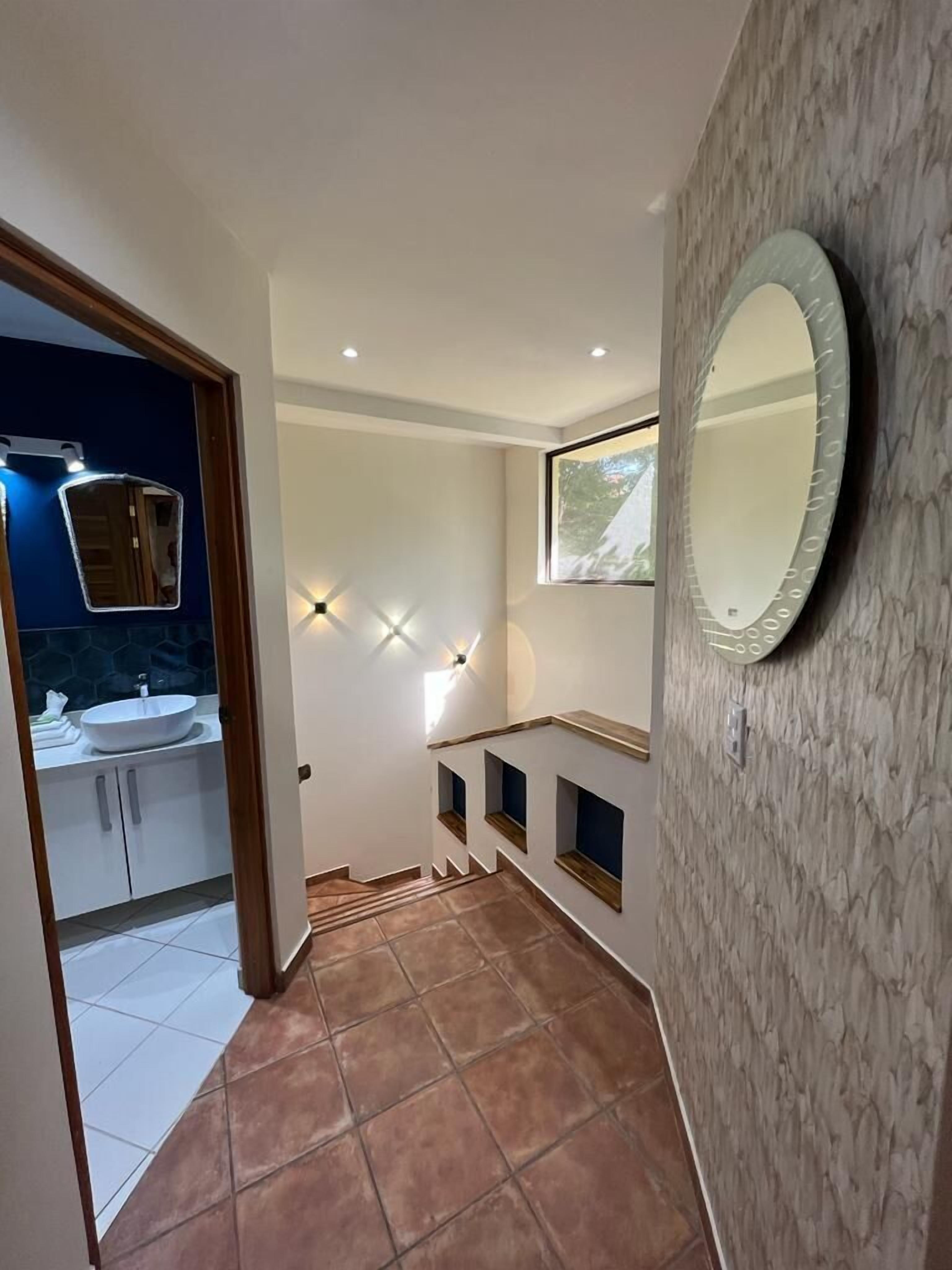 A modern bathroom with a vanity, a large mirror, and a tiled floor.
