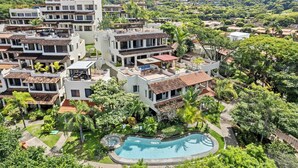 A residential area with modern buildings, a swimming pool, and lush greenery. - Tropical Gardens (Sardinal)