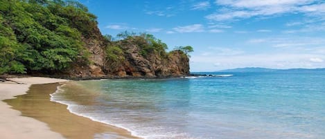 Una playa cerca, arena negra, camas de playa, toallas de playa